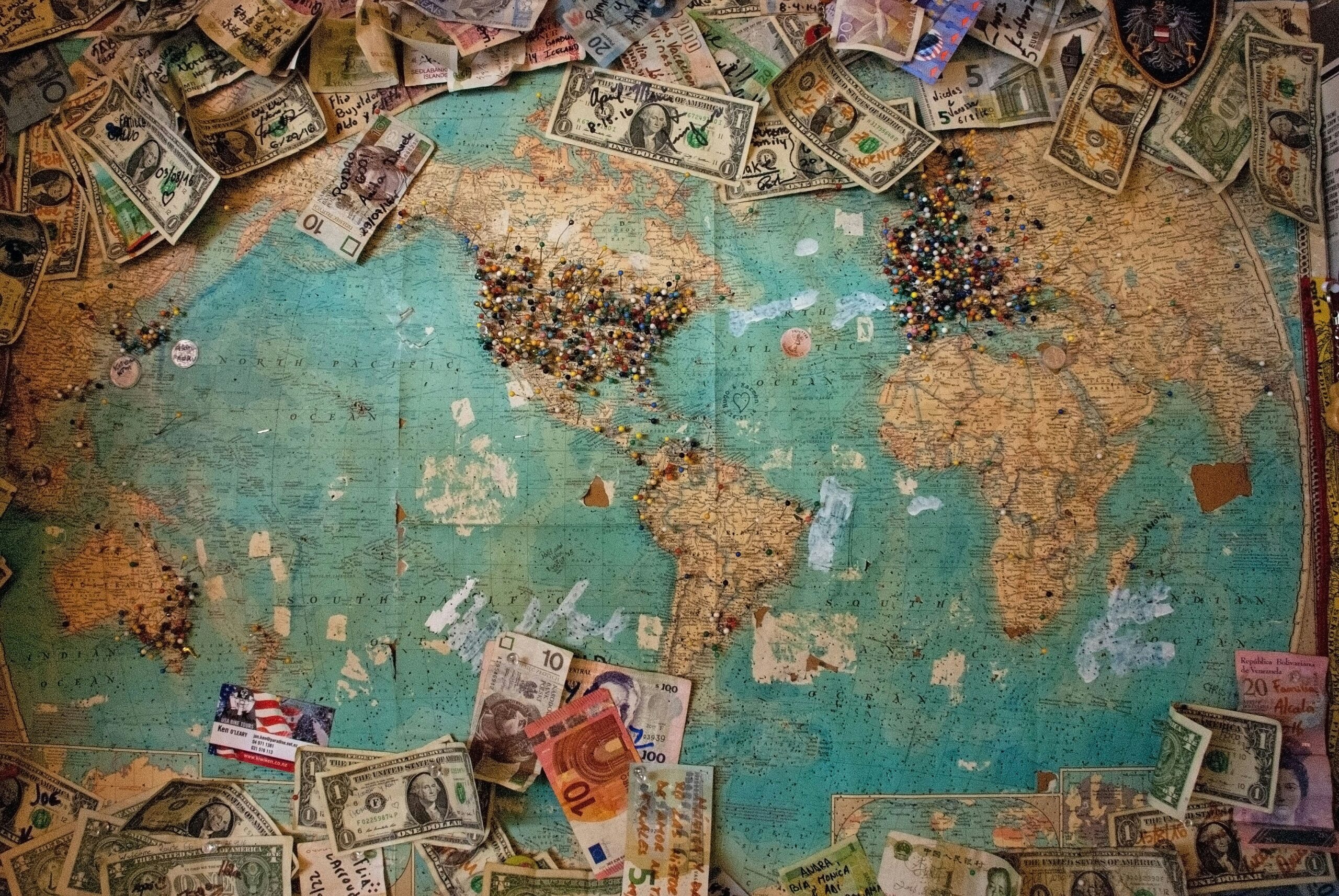 Map of the world with money to plan traveling on a budget.